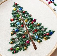 a small christmas tree made out of buttons on a white wall hanging from a hoop