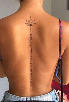 the back of a woman's body with a lotus tattoo on her lower back