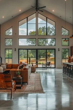 a large open living room with high ceilings and lots of windows on both sides of the room