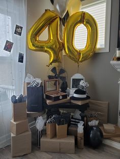 a table topped with boxes and balloons in the shape of numbers 40, 50 and fifty