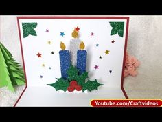 a handmade christmas card with two candles and holly wreaths on the front, surrounded by stars