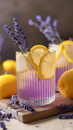 two glasses filled with lemonade and lavender on a wooden tray next to some lemons