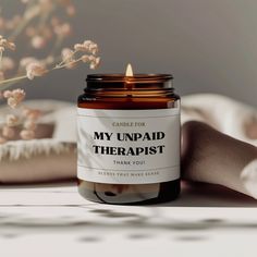 a candle that is on top of a table next to some flowers and a blanket