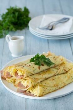 an omelet with ham and cheese on a white plate next to a cup of coffee