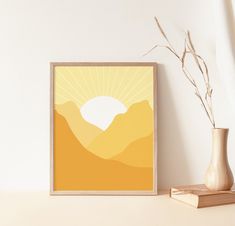 an art print is displayed on a shelf next to a vase with dried grass in it