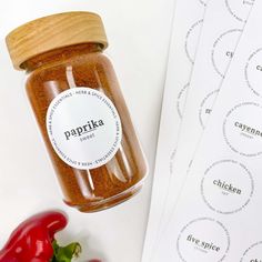 a jar of paprika spice next to some red peppers on a white table