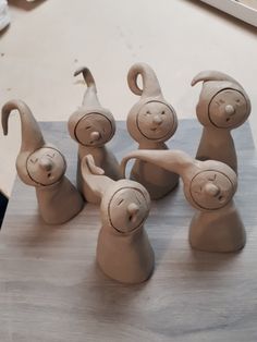 five clay animals sitting on top of a wooden table