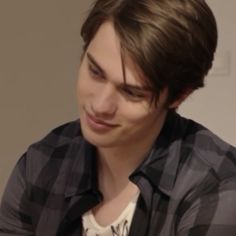 the young man is looking at his cell phone while wearing a black and white checkered shirt