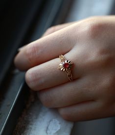 a close up of a person's hand wearing a gold ring with flowers on it