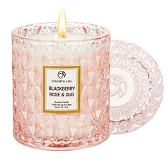 a pink glass candle with a white label on the front and side, next to a plate that says blackberry rose & oud