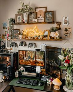 a desk with a computer, keyboard and various pictures on the wall