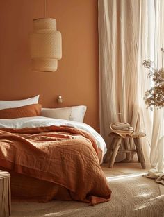 a bedroom with an orange wall and white curtains