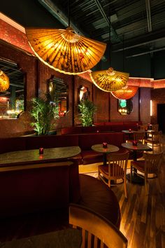 the interior of a restaurant with wooden tables and umbrellas hanging from the ceiling above