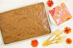 a cake sitting on top of a pan covered in frosting next to orange flowers