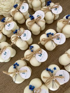 small white pumpkins tied with twine and blue flowers are arranged on a table