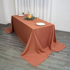 the table is set with plates and glasses on it, along with an orange cloth