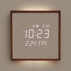 a cross - stitch clock is displayed on the wall next to a lamp with a wooden frame