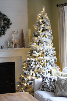 a decorated christmas tree in the corner of a living room with white and silver decorations