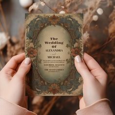 a person holding up a wedding card in front of some dried flowers and branches with the words'the wedding of alexandria'written on it