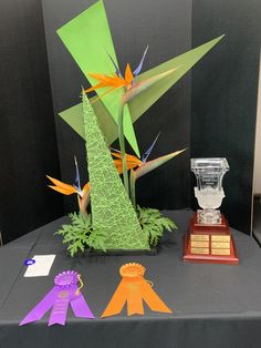 an arrangement of paper birds and ribbons on display in a museum exhibit area with award plaques