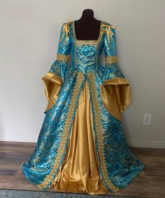 This striking gown is made from a vibrant turquoise blue, designer damask with a ornate gold pattern woven throughout.  The bodice features a deep, square neckline trimmed with gold braid to accentuate your decoletage. The gathered overskirt is firmly attached to the bodice, and is also trimmed with a stunning wide braid down the skirt fronts for a lovely elegant line.   The dramatic great sleeves are trimmed with the wide gold braid at the elbow, and the wide bell sleeves can be turned back to reveal the gorgeous gold lining.  The sleeves can be made attached or detachable. Closes at the back through brass grommets which allows for a more adjustable fit, and backed with a modesty panel. This bodice is boned along the front/side seams and at the grommet back closure. The gold underskirt is Blue Rococo Dresses For Costume Party, Blue Historical Dress For Costume Party, Blue Historical Costume Party Dress, Blue Historical Design Dress For Costume Party, Blue Rococo Style Costume Dress, Elegant Blue Gown For Fancy Dress, Blue Rococo Costume Dress, Blue Baroque Wedding Dress, Blue Baroque Dress With Historical Design