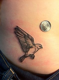 a small bird tattoo on the side of a woman's stomach with a penny