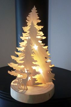 a small wooden christmas tree with lights on it's base and a deer figurine next to it