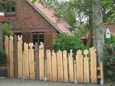 a wooden fence with birds on it in front of a house