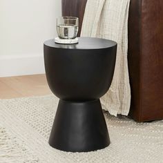 a black table with a glass on it in front of a brown leather chair and white rug