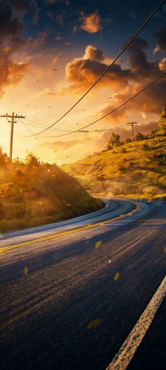 the sun is setting over an empty road