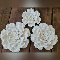 three white flowers sitting on top of a wooden table