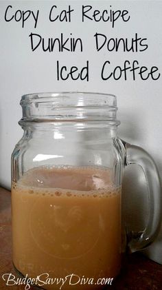 a glass jar filled with liquid sitting on top of a counter next to a sign that says copy cat recipe, dunkin donuts iced coffee