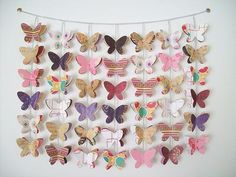 a bunch of butterflies are hanging on the wall next to a white wall and some string