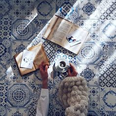 a person sitting at a table with an open book and coffee cup in front of them