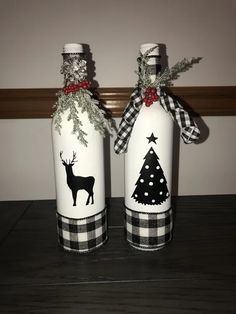 two wine bottles decorated with christmas trees and deers are sitting on a wooden table