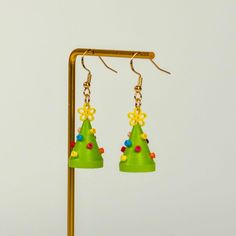 a pair of green earrings with yellow flowers and beads hanging from it's earwires