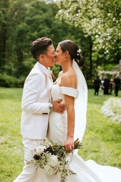 a bride and groom are standing in the grass