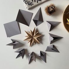 an arrangement of folded origami pieces on a table next to a candle holder