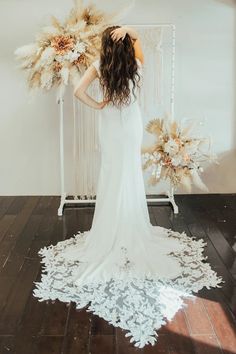 a woman standing in front of a white wall with flowers and feathers on the floor