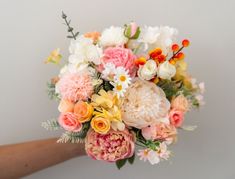 a person holding a bouquet of flowers in their hand with white and pink blooms on it