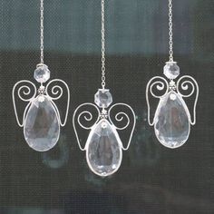 three angel necklaces hanging from a window