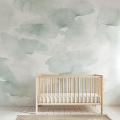 a baby's crib in front of a painted wall with clouds on it