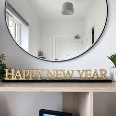 a mirror sitting on top of a wooden shelf in front of a wall mounted tv