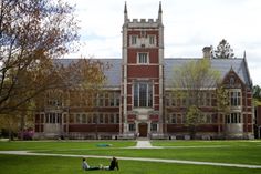 two people sitting on the grass in front of a building