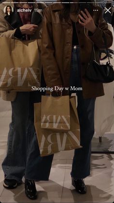 two women are holding shopping bags and looking at their cell phones