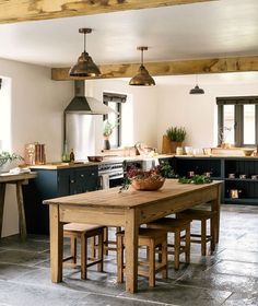 a kitchen with an island table and stools in the center, surrounded by potted plants