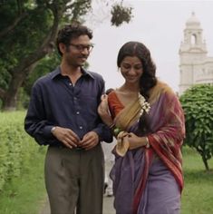 a man and woman standing next to each other in front of a tree filled park