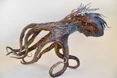 an octopus sculpture made out of branches and other things is shown on a white background