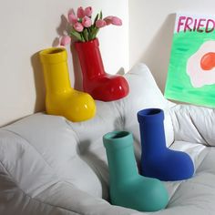 three colorful vases sitting on top of a white couch in front of a painting