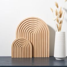 a vase with some flowers in it next to two wooden coasters on a table